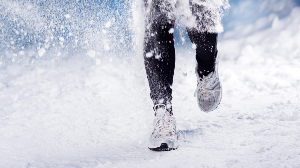 Juoksija lenkkarit jalassa lumisella tiellä.