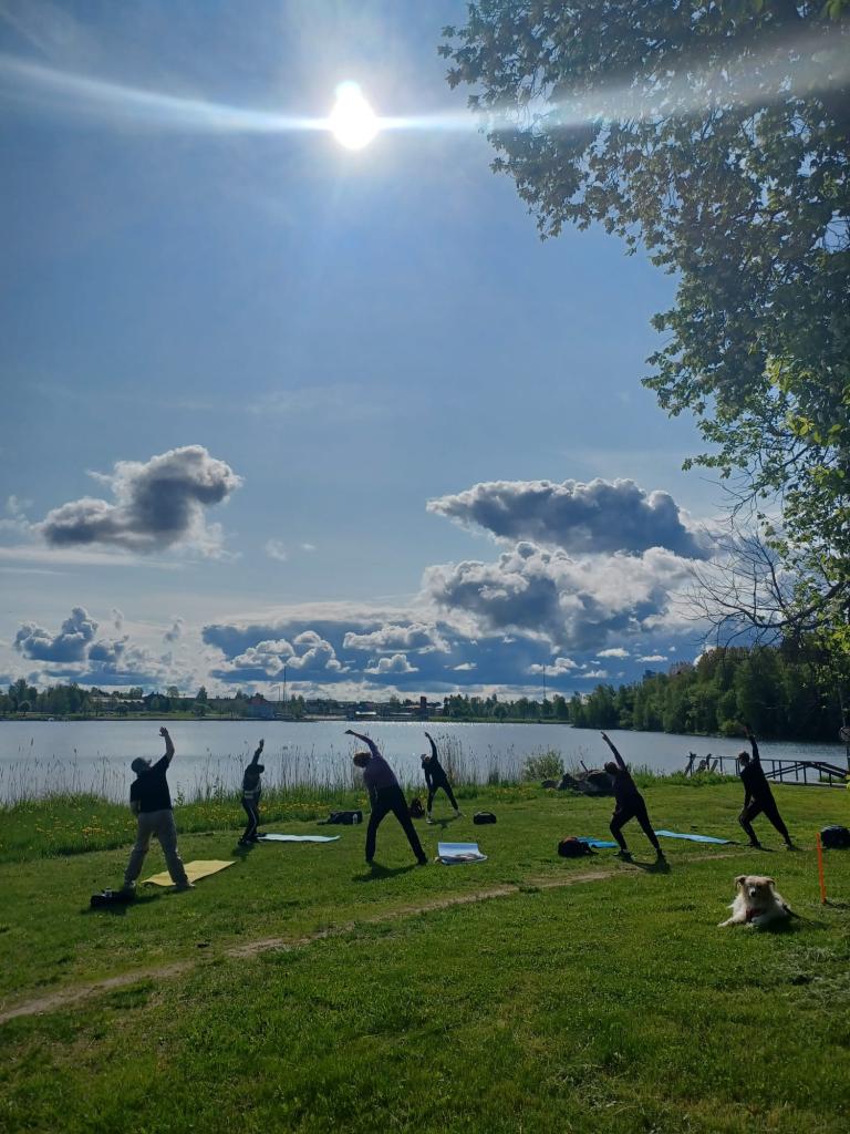 Ihmisiä jumppaamassa meren rannalla auringon paistaessa.